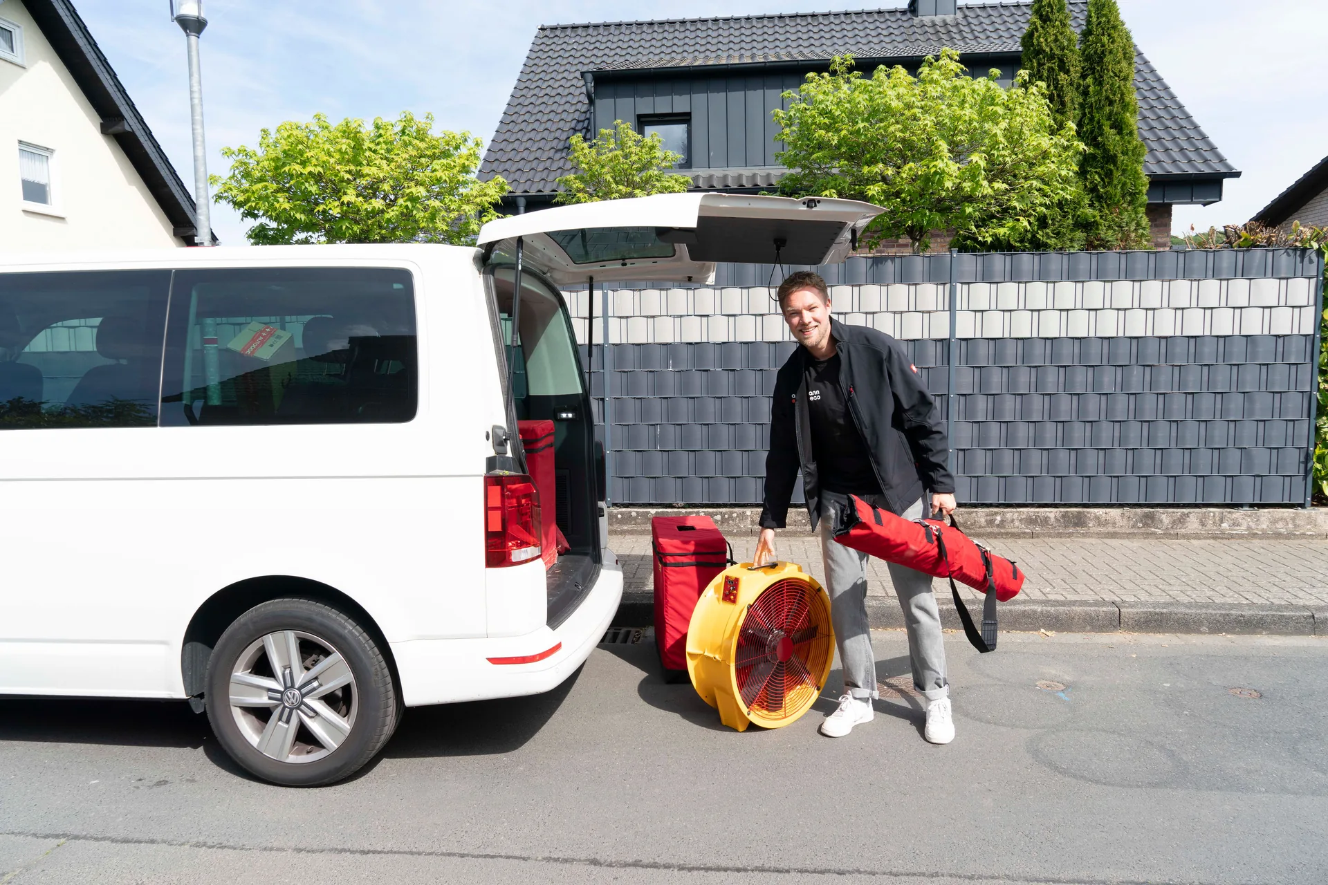 Benedikt Aumann mit Blower-Door-Prüfgerät vor Einsatzfahrzeug