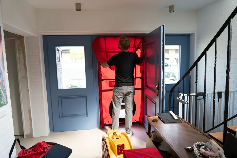 Blower-Door-Messaufbau mit rotem Lüfter in einer Haustür